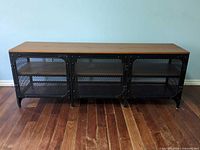 Front view showing entire TV stand, three mesh doors, wood top