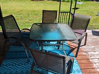 Full view of patio dining set showing glass table and four chairs