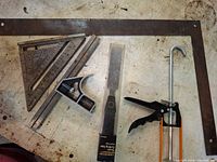 Lot overview of saw, rulers, squares, straight edge, caulk gun