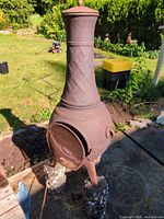 Full view of cast iron chiminea showing chimney, body, legs and rust finish