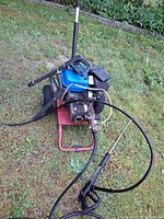Full view of pressure washer with hose and gun attached on lawn
