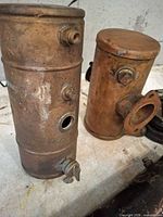 Two copper/brass cylindrical exchangers standing upright with visible threaded ports and flange