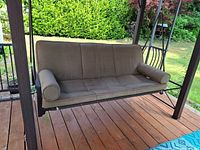 Front view of suspended bench swing with cushion and bolsters