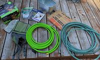 Lot overview: hoses, planter, tote with gloves, books, NOMA solar lights boxes, yard-waste bags