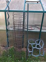 Group view of metal tomato cages, green stakes and one plastic mold