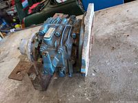 Side view of gearbox showing blue housing and rust on bracket
