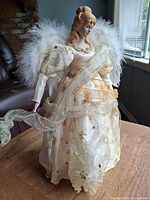 Full front view of angel tree topper showing dress, wings and ribbon