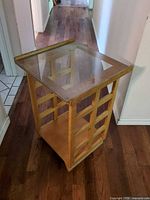 Three-quarter view of light wood lattice side table with glass top