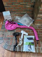 All five items arranged together: two hair dryers, pink bonnet attachment, Mainstays vacuum bags box with loose bags, sealed RAKII posture corrector