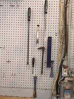 Overall view of seven hand tools hanging on pegboard