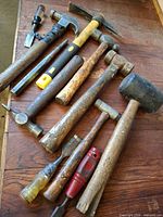 Overview of hammers, mallet, chisels laid on wood surface