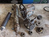 Tabletop view of two cylinders, gearbox with pulley, hydraulic pump/motor, assorted couplings