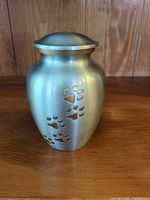 Front view of brushed silver urn showing paw print design