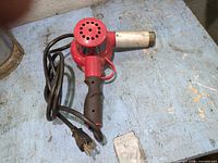 Full view of red corded heat gun with cord and plug on work surface