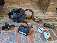 Overview of entire lot on brick floor showing camera bag, dashcam with mount, HDD dock, cable, two Wi-Fi repeaters, monocular and Sony camera