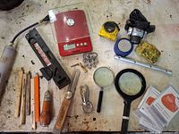 Overview of lot showing scale, hand tools, magnifiers, tape measure, multi-tool, rotary tool, pencils