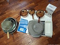 Group shot showing saucepans, lids, bakeware, colanders, strainer, ice packs and boxed meat grinder