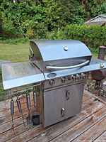 Full front view of grill showing burners, side shelves and hanging tools