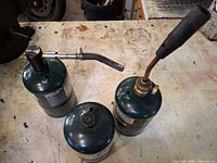 Three Coleman propane cylinders; two fitted with torch attachments
