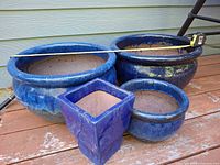 Group view of four blue glazed ceramic planters on deck