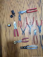 Group shot of all pliers, film canister and loose tips on wood surface