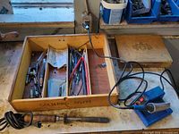 Overview of wooden box with soldering irons, tips and heat shrink; blue controller base visible