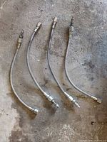 Four stainless braided hoses laid out showing overall condition and fittings