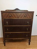 Front view showing five drawers, brass hardware, carved columns, turned legs