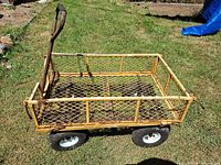 Side view of yellow steel mesh wagon on lawn showing pull handle and four pneumatic tires