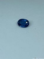 Top view of oval blue sapphire on white surface