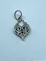 Front view of silver heart pendant showing filigree design and bail