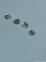 Four loose round brilliant cut diamonds on white background