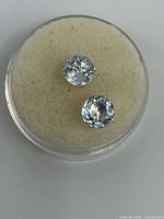two round aquamarine studs in clear case on foam insert