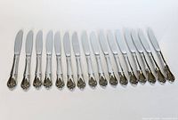 Sixteen Arbor Rose dinner knives aligned side by side