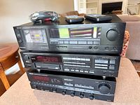 Stacked view of receiver, CD changer, cassette deck with remotes and cables on top