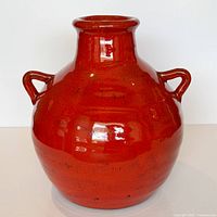 Front view of red glazed ceramic vase with handles