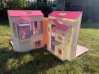 Folded-open Barbie dollhouse on lawn showing exterior walls, roofs, hinges