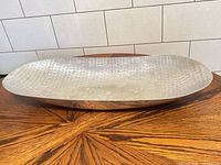 Full view of elongated hammered aluminum bowl on table