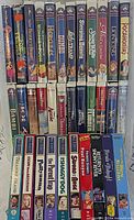 Front spines of 24 Disney VHS tapes in clamshell cases