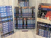 Front view of full 64-tape lot in clear bin showing episode and movie spines