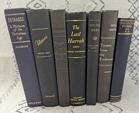 Front spines of all seven hardcovers showing titles and authors