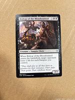 Front of Bishop of the Bloodstained card showing artwork, mana cost, text, power/toughness, collector number 97/279