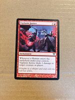 Front view of Vigilante Justice card showing artwork, title, mana cost, type line, text box, set symbol and artist credit