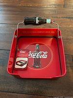 Top view of red metal napkin holder showing Coke graphics and weighted bottle bar