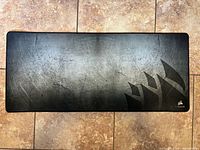 Full view of large black Corsair desk mat on tile floor