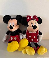 Front view of Mickey and Minnie Mouse plush toys sitting side by side