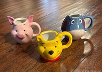 Front view of all three character mugs: Piglet, Winnie the Pooh, Eeyore