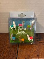 Front of sealed package showing six multicolour llama wine markers