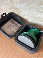 Orbital buffer inside hard case with manual and polishing pad visible