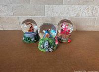 Front view of all three Disney Winnie the Pooh mini snow globes